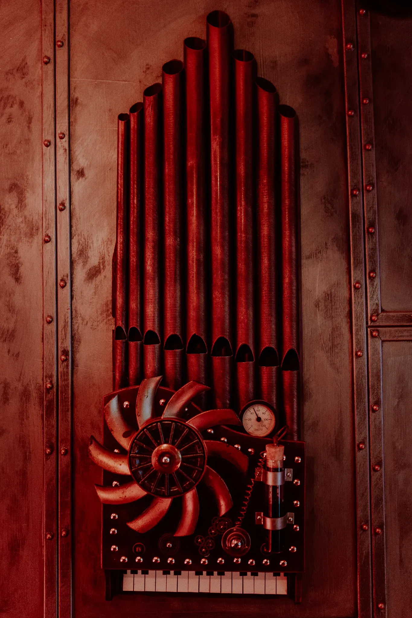 L’orgue à vapeur du décor, ses tuyaux, son hélice et son manomètre sur une paroi rivetée
